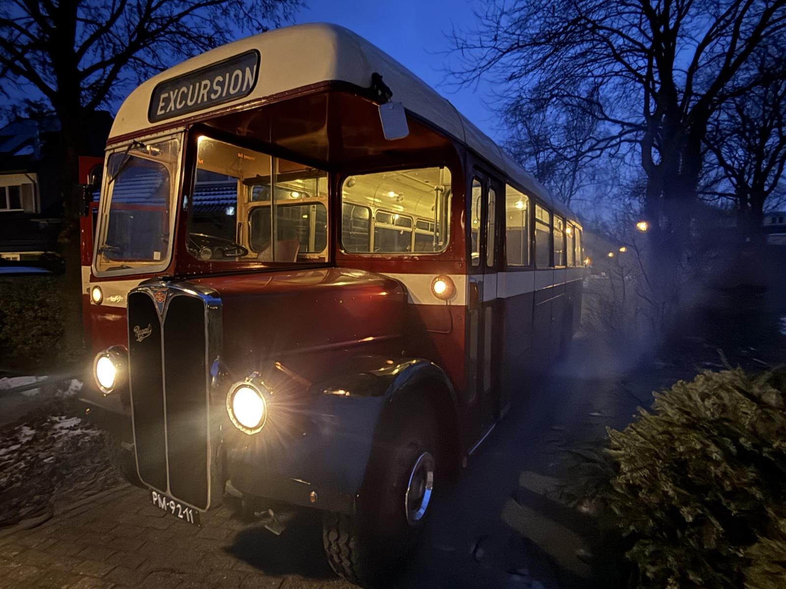 De bus met brandende koplampen in de schemer