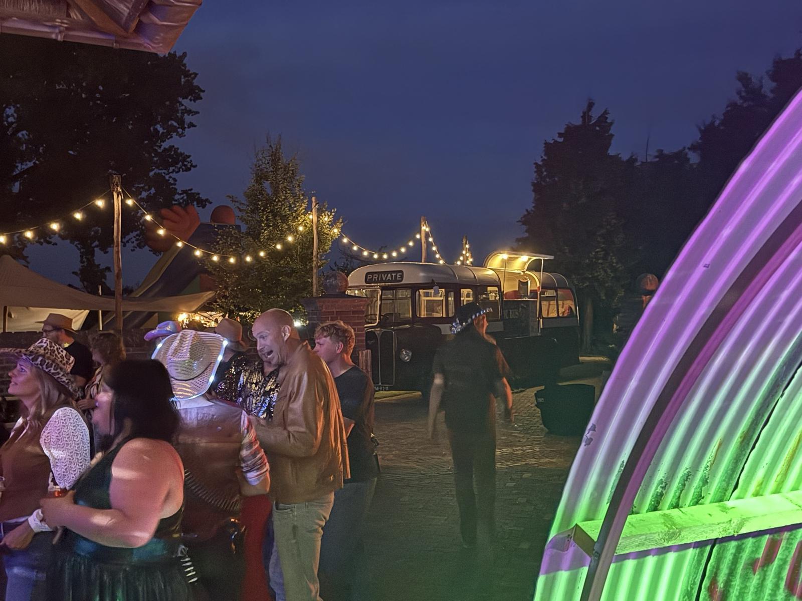 Festivalgangers bij de bus in de avond