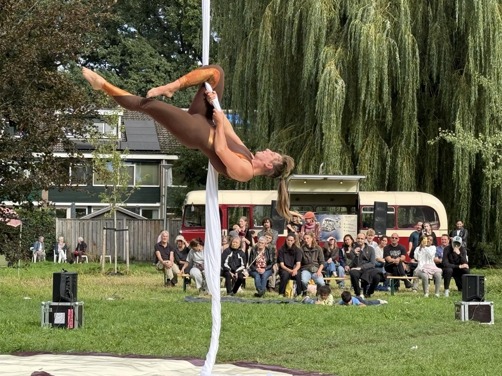 Acrobate aan doeken met de bus op de achtergrond