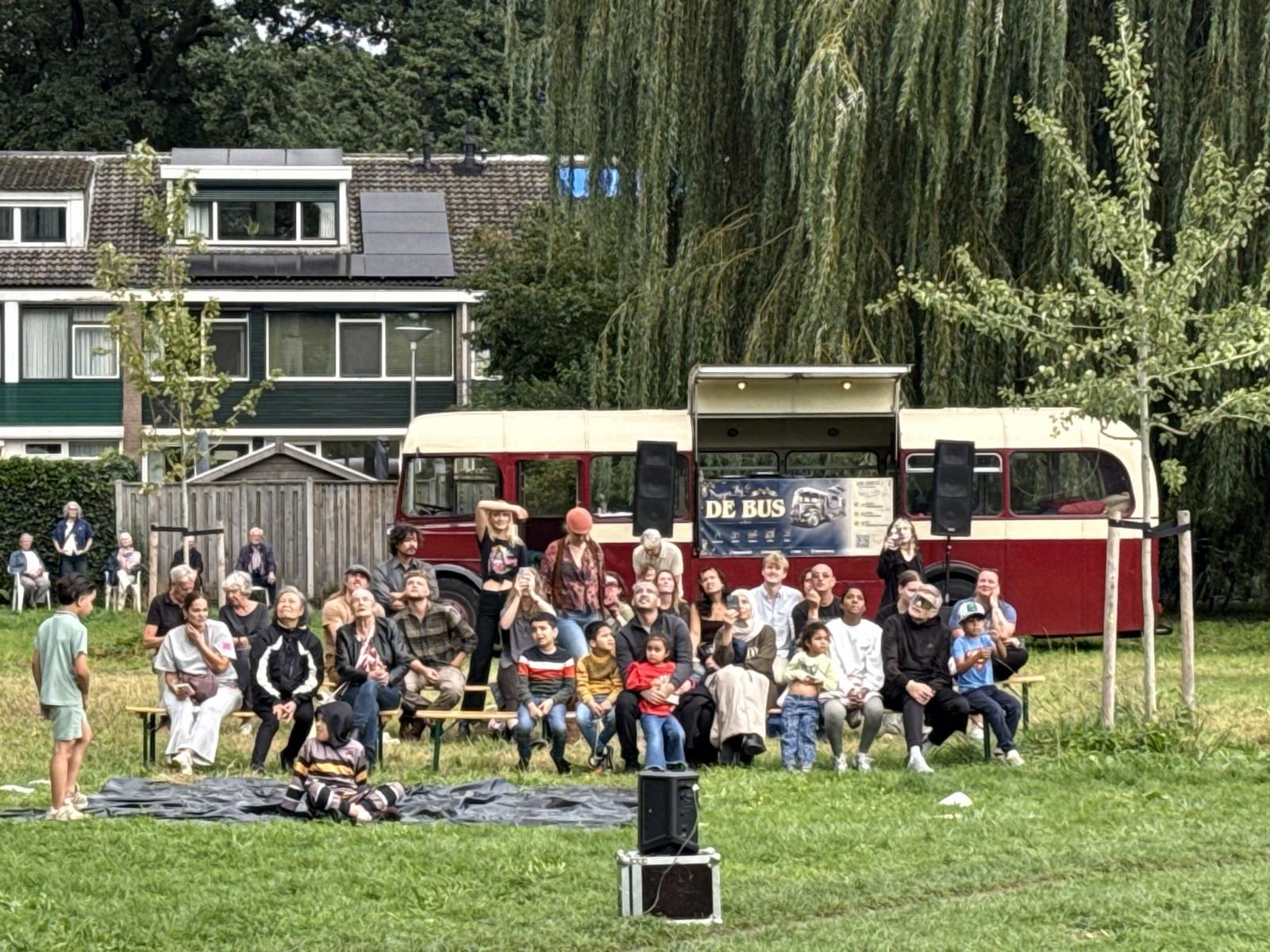 Publiek op het gras voor de bus