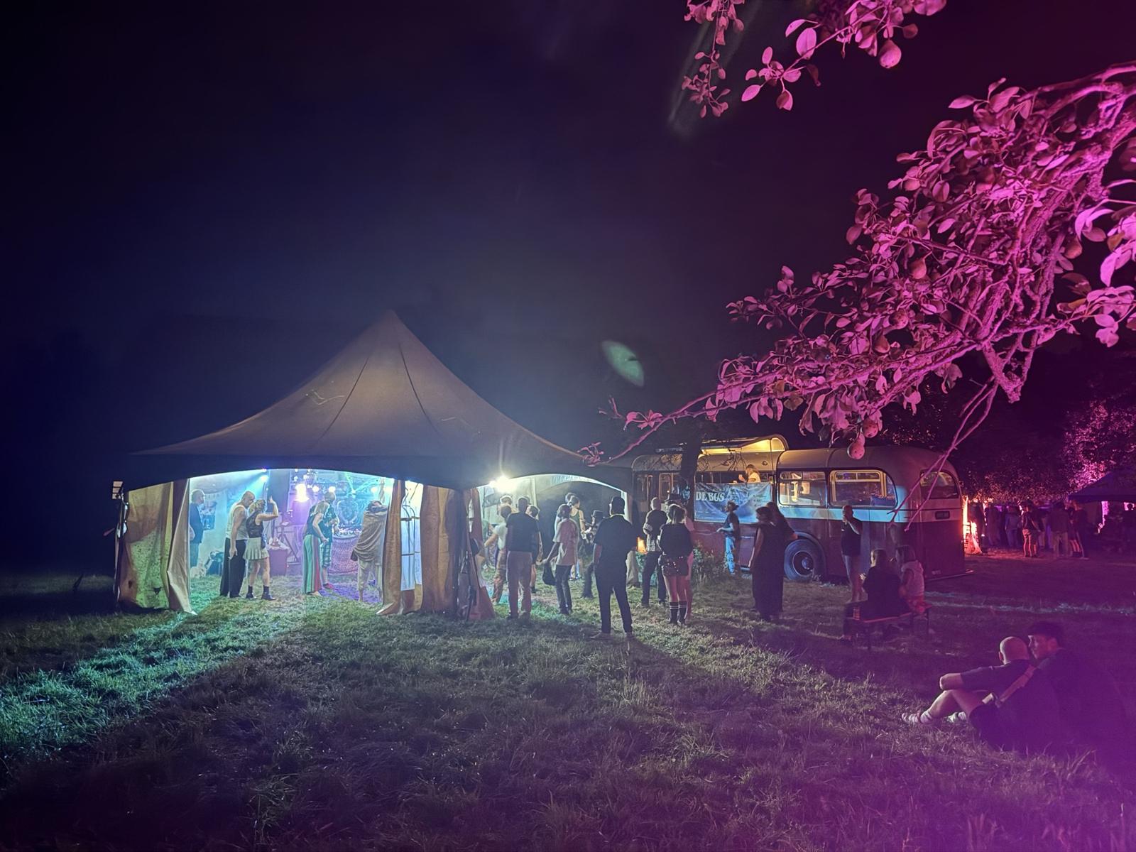 Verlichte tent en de bus in de nacht